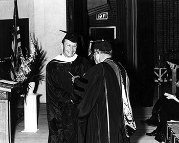 black and white photo of Walter Schrader receiving his diploma at Commencement in
                              1969