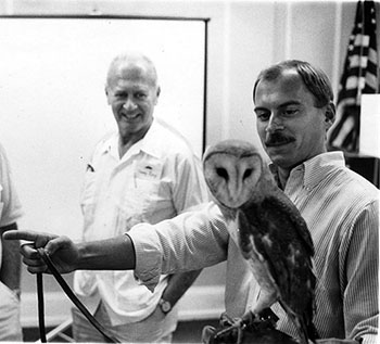 black and white photo of Keith Bildstein holding an owl in a classroom