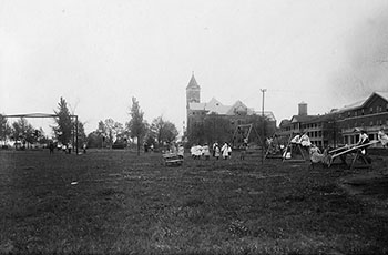 black and white photo of children on the playground in front of Bancroft hall