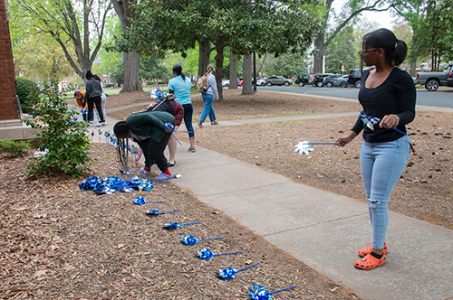 Social Work faculty and students setting up blue pinwheels in the garden outside of
                        Bancroft Hall