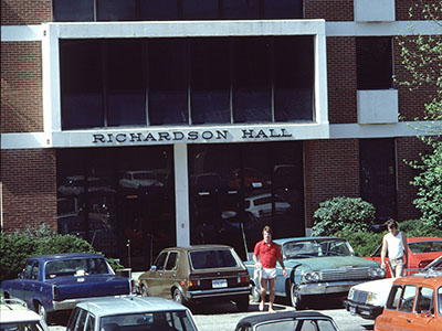 Building named Richardson Hall with cars parked in front. Color
