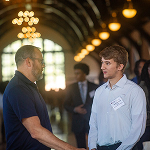 a firm representative speaking with a student in professional attire at a Meet the
                           Firms event