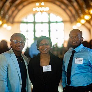 three students in professional attire smiling at a Meet the Firms event