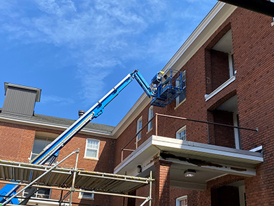 Blue sky; person standing in crane working on roof trim