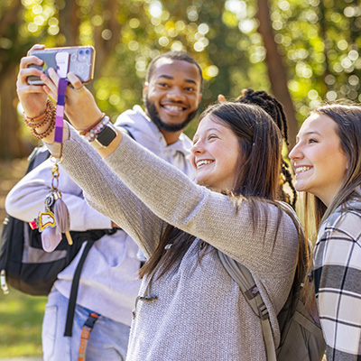 three students taking a selfie with a cell phone