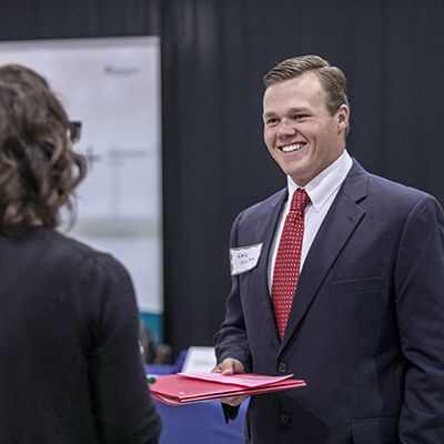 a student in a suit smiling at an event