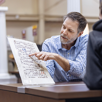 Man sitting at a table and showing someone as printed manuscript