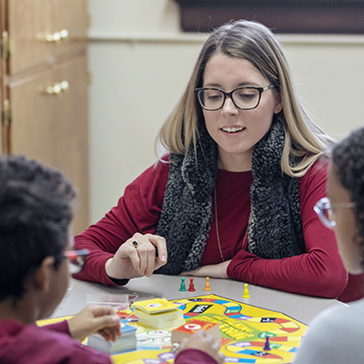 Woman sitting with kids at a table playing boardgames