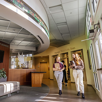 Two students walking through a business building on campus