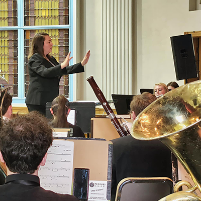 Woman in a suit conducting a large student orchestra