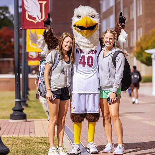 Two students standing with Winthrop's mascot Big Stuff